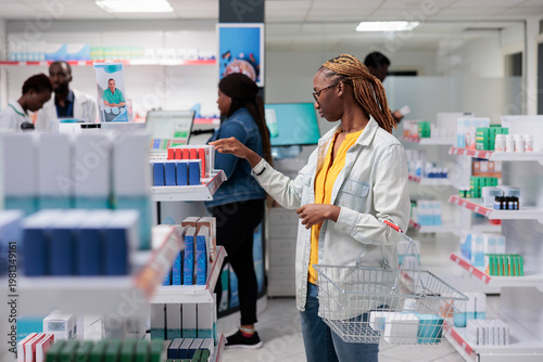 Konstfotografi African american woman checking medications in drugstore shelf, looking at tablet packages