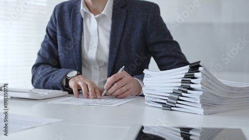 Obraz na plátně Accountant or bookkeeper calculating financial data, preparing taxes, managing business reports, and organizing paperwork with a calculator and stack of documents on an office desk