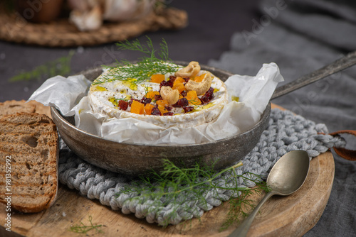 Wallpaper Mural A gourmet close-up of melted Camembert cheese topped with sweet dried apricots, tart cranberries, and crunchy cashews, drizzled with olive oil and fresh dill for a perfect rustic appetizer Torontodigital.ca