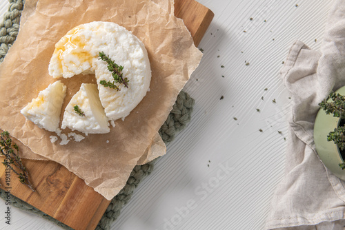 Wallpaper Mural High angle horizontal view of sliced white cheese drizzled with golden honey and fresh thyme on parchment paper and a wooden board in a bright kitchen Torontodigital.ca