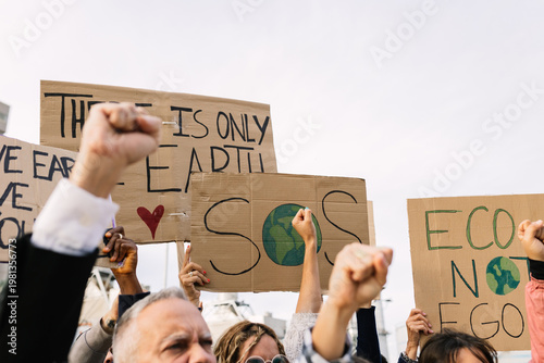 Foto Activists raising fists and holding cardboard signs at a protest, advocating for