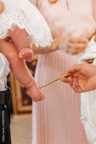 Fotografía A close-up of a priest using a golden brush for the holy anointing ritual on a newborn baby's feet during a traditional Orthodox christening