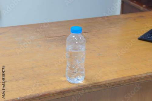 A clear plastic bottle of water sits on a wooden table