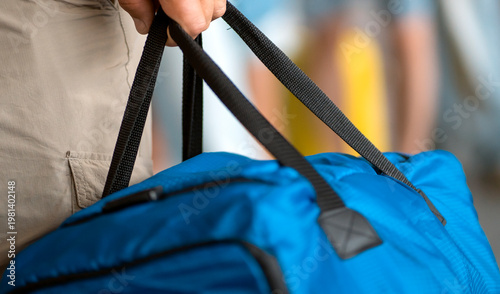 A traveler is holding a blue bag, luggage closeup view.