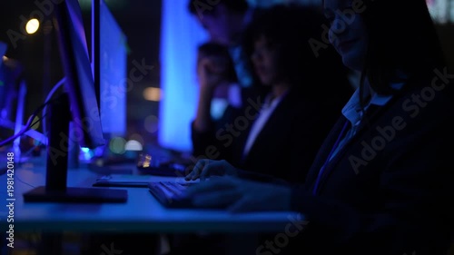 Inclusive business collective of experts including african american woman and asian male overseeing complex electronic systems and software code inside a modern futuristic corporate laboratory.