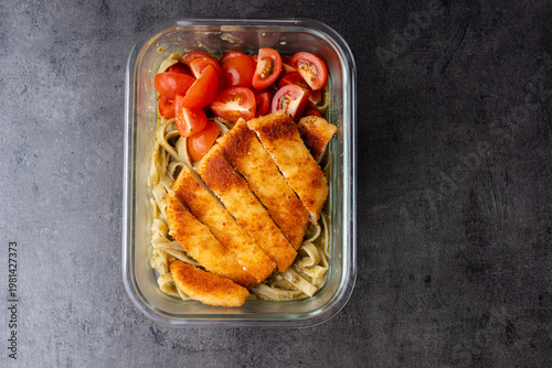 chicken schnitzel on pesto pasta with diced cherry tomatoes meal prepped