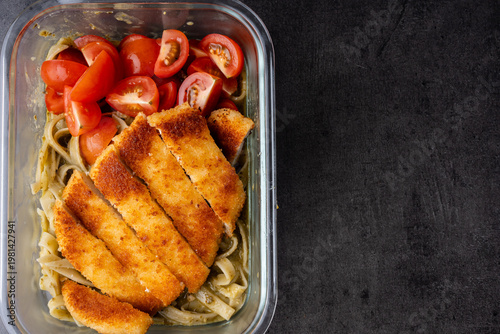 chicken schnitzel on pesto pasta with diced cherry tomatoes meal prepped