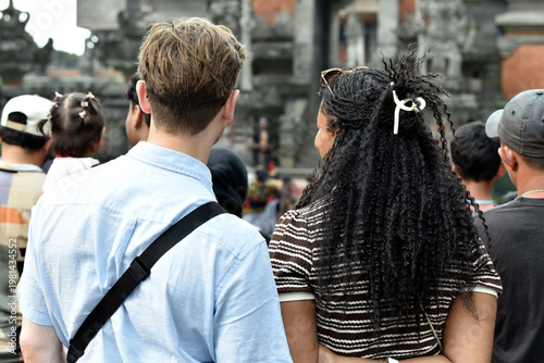 Fotografia A young couple from different ethnicities looks engrossed in watching an event or performance in the photo from the background