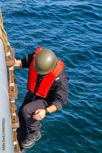 A Marine Special Forces soldier climbs a rope ladder onto a vessel violating maritime territorial boundaries during a maritime security mission.