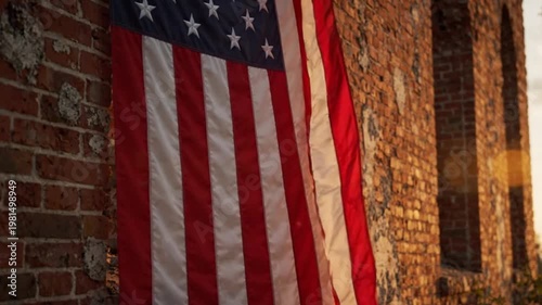 American flag hangs on a brick building with a window at sunset