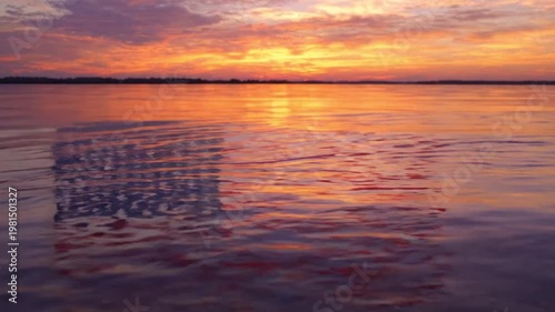 Sunset over calm water with vibrant sky reflection ripples