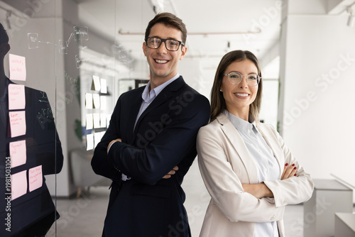 Bild auf Leinwand Young 30s Spaniard businesspeople, motivated employees professionals looking at camera, standing confidently side by side in modern workspace, engaged in productive teamwork