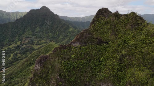 Aerial shot of dramatic mountain peaks covered in lush tropical vegetation. Sharp ridgelines in foreground with view across the full mountain range