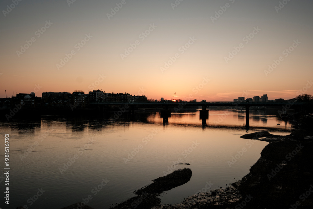Obraz premium River sunset reflecting city skyline and bridge at dusk