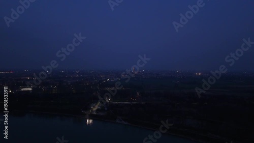 Aerial view of Cremona city and Po river at dusk with city lights twinkling