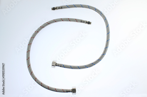 Flexible hoses lie coiled neatly against a clean, white background. Metal fittings cap each end, ready for attachment, highlights the product's utility and durability, isolated on white background 