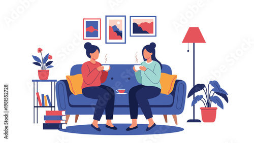 Two female friends sitting on a comfortable blue sofa in a cozy living room while having a friendly conversation and enjoying warm cups of hot tea.