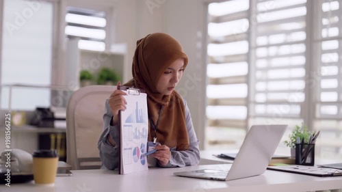 Asian adult woman in hijab presents data charts online video meeting remote work from home office professional business report analysis