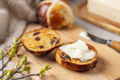 Delicious Easter Hot Cross Buns wiht Butter on wooden Board. Sweet Bread. Holiday Food