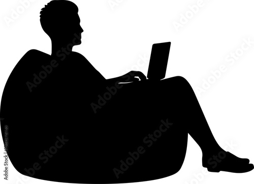 Silhouette of a man sitting in a bean bag chair while working on a laptop computer
