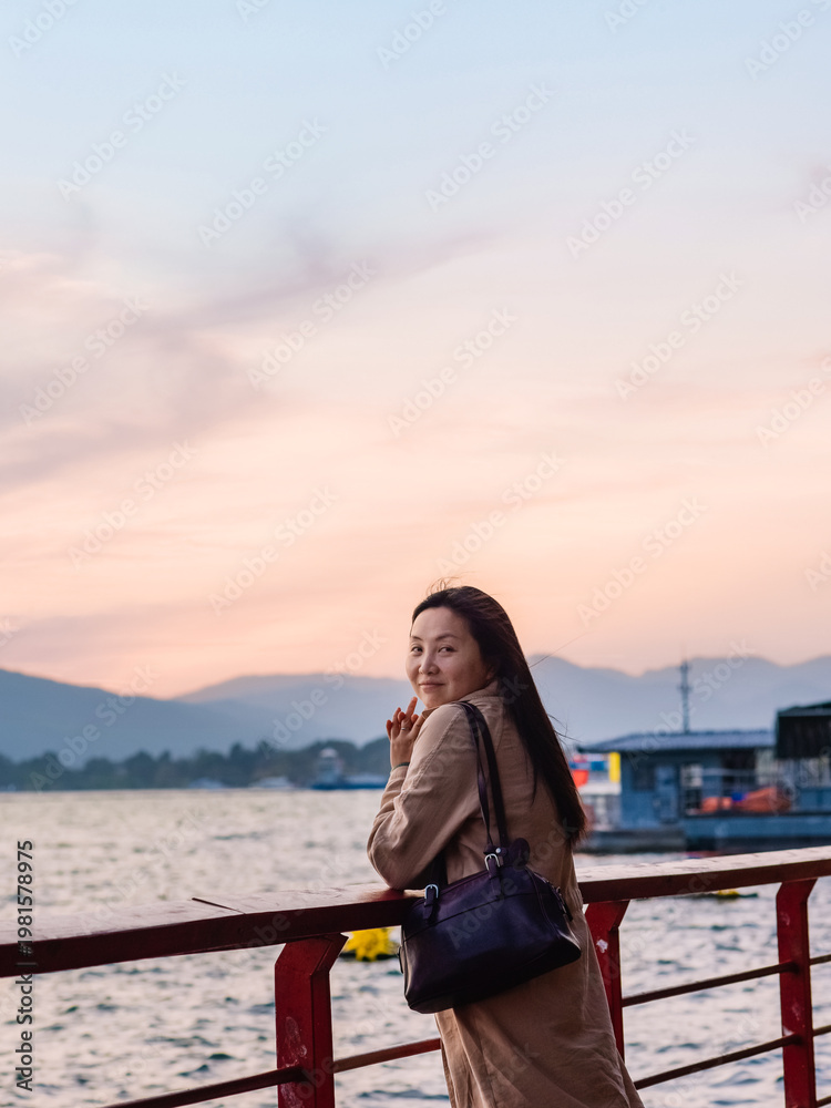 Fototapeta premium Asian woman tourist watching the sunset over Dianchi Lake at Haihong Wetland Park in Kunming, Yunnan, China