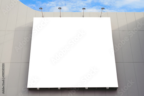 A large blank billboard on a gray building with a blue sky
