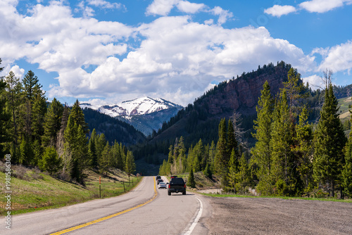 Open highway road trip through the majestic Rocky Mountains of the American West under a blue sky.