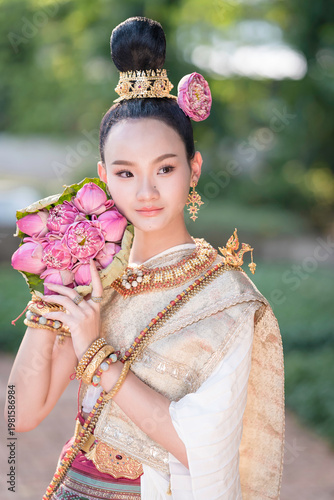 Thai Woman in Traditional Costume Holding Pink Lotus, Elegant Cultural Portrait.