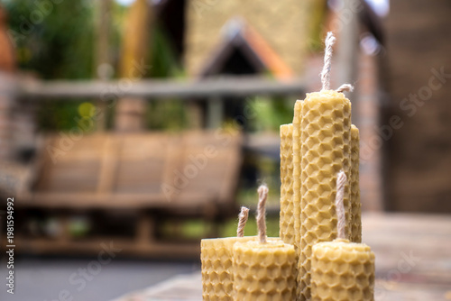 Wallpaper Mural Handmade beeswax candles with twine wicks displayed in a rustic setting and a blurred chapel in the background, in Brazil.  Torontodigital.ca