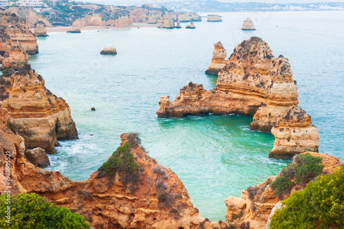 Yellow sandstone rocks and turquoise water on the coast of Atlantic ocean in Algarve, Portugal. Beautiful seascape at foggy morning.