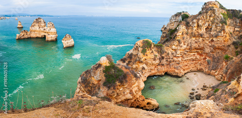 Yellow sandstone rocks and turquoise water on the coast of Atlantic ocean in Algarve, Portugal. Beautiful seascape at sunset.