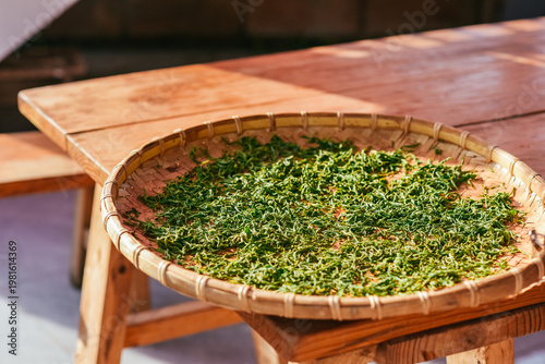 Fresh green tea leaves drying in bamboo trays at a Pu'er tea plantation in Pu'er, Yunnan, China