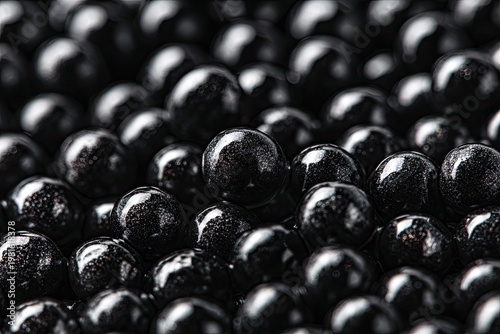 Heap of glossy, dark black spheres filling the frame, with focus on center foreground