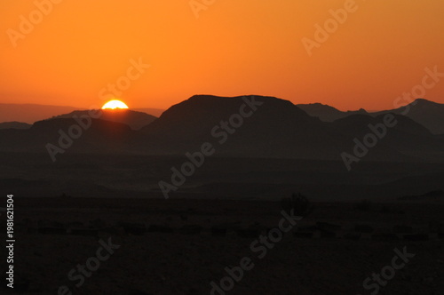 Sunset over mountains in a vast desert landscape during evening hours