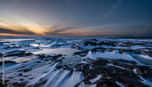 Stunning Sunset Over Icy Rocky Shoreline in Winter.