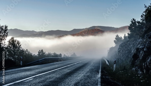 Misty Road Winding Through Forested Mountains at Dawn.