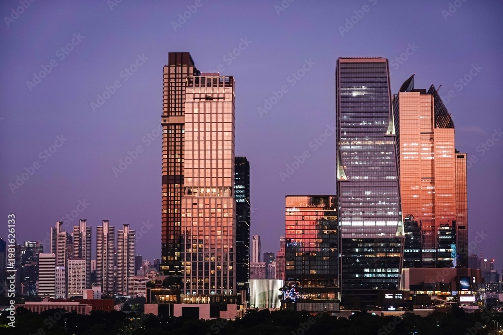 Naklejka premium Beautiful Bangkok skyline during sunset purple sky with modern glass skyscrapers reflecting warm golden light. Urban cityscapes and travel destinations in Bangkok,Thailand Southeast Asia.