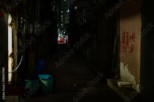 A dimly lit back lane in Jordan, Kowloon, Hong Kong, with Chinese graffiti on a weathered wall and a glimpse of a busy street beyond