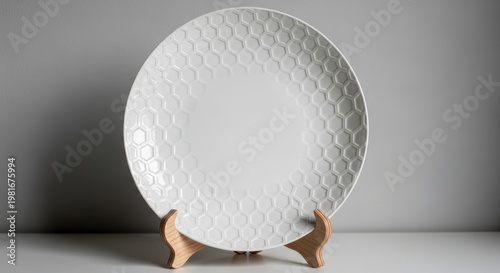 White porcelain decorative plate with embossed honeycomb pattern on a wooden stand