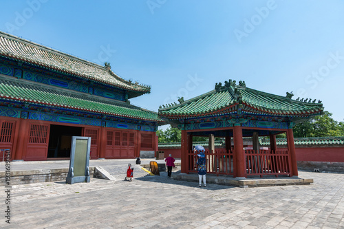 A traditional red-and-blue hall with green-tiled roofs stands in the Temple of Heaven complex in Beijing under a clear blue sky. Beijing, China - 28 May 2025