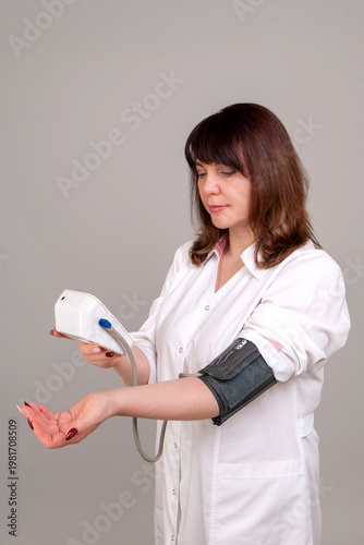 A female medic measures blood pressure with an automatic tonometer.