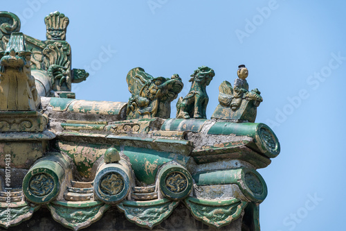 Intricate green glazed roof decorations featuring mythical beasts and figures adorn the eaves of a traditional building at the Temple of Heaven in Beijing.