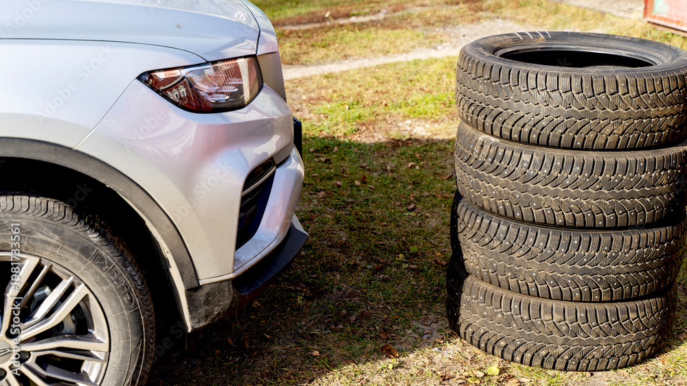 Obraz premium Silver SUV parked beside stacked tires