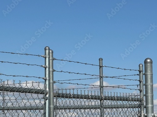 Barbed wire security fence with metal posts showing perimeter protection and restricted boundary infrastructure