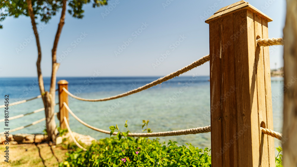 Naklejka premium Sunlit wooden posts frame a tranquil coastal path