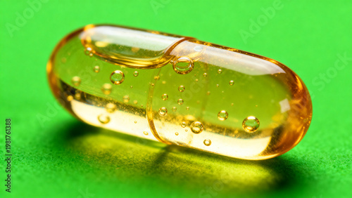 Premium macro shot of a transparent golden softgel medical pill filled with liquid oil and air bubbles inside isolated on a solid bright chroma key green screen background for medical design