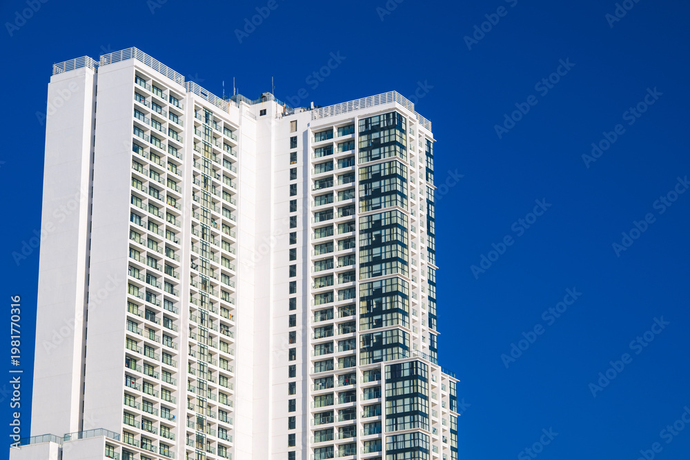 Fototapeta premium facade of the tall modern new skyscraper of hotel against the background of the blue sky