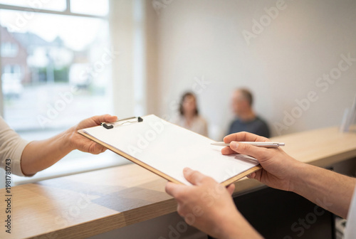 Receptionist handing a clipboard to a patient in medical office