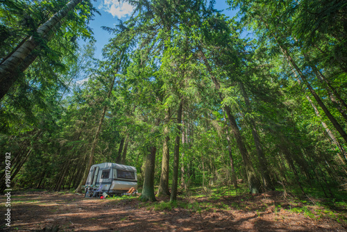 White Caravan Trailer Parked in Dense Green Forest with copy space