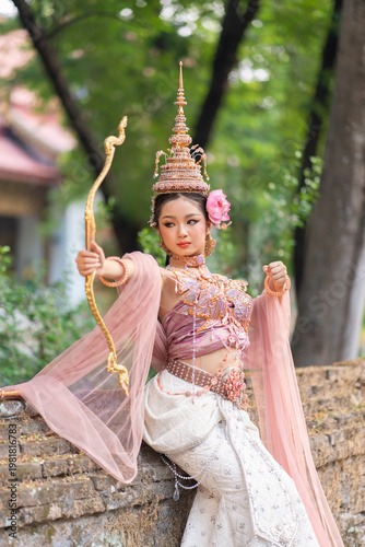 Beautiful Songkran goddess dressed in traditional attire poses gracefully with golden bow embodying Songkran queens elegance and charm